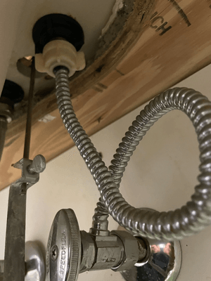 A metal hose connected to a pipe

Description automatically generated