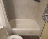 A bathroom with a white bathtub and toilet

Description automatically generated